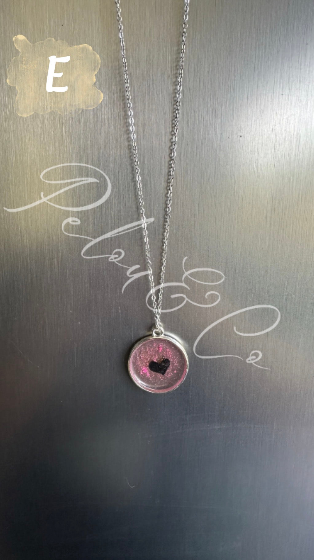 Pendentif et sa chaîne en acier inoxydable argenté avec un cœur tacheté de rose
